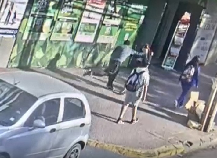 Esta captura del video muestra el momento en que el enajenado mental golpea en el rostro a la joven.